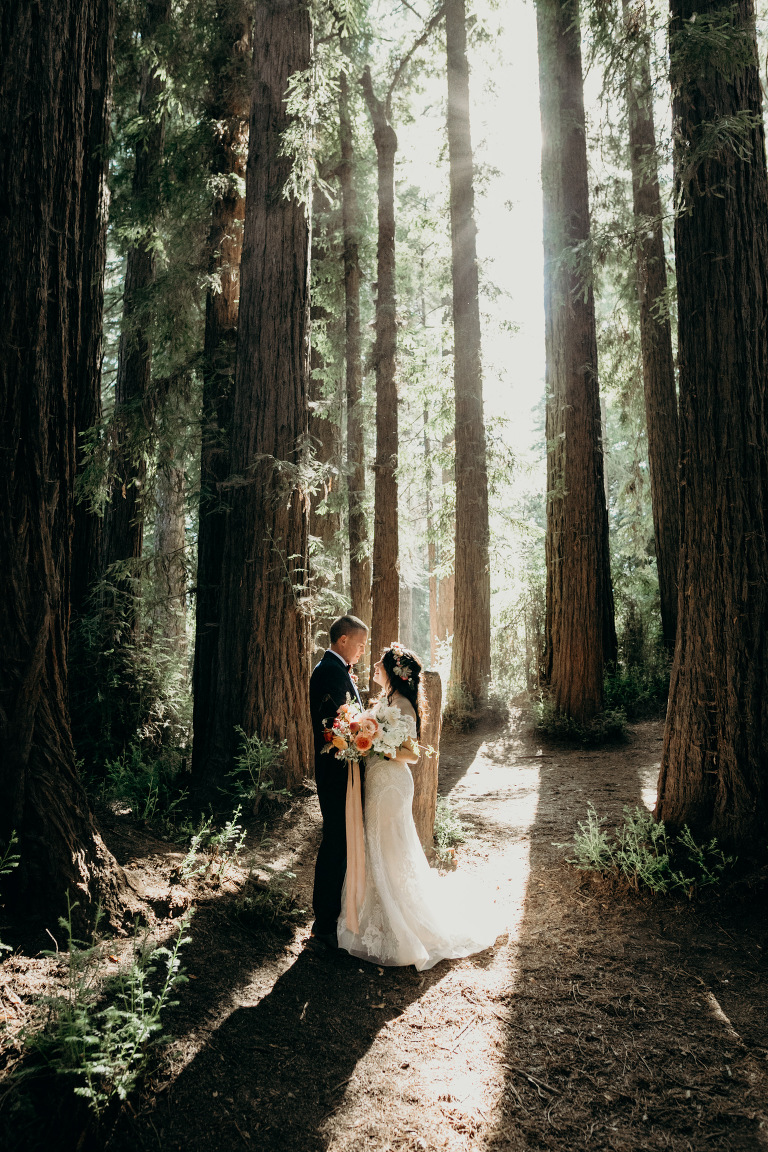 A bride and groom stand in the woods at Roaring Camp, one of the best redwood forest wedding venues in California