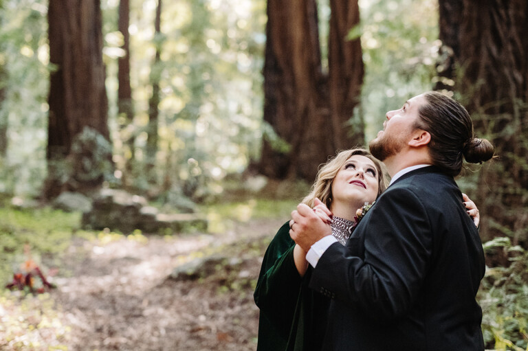 a newlywed couple admires the redwood trees above them during their first dance as husband and wife