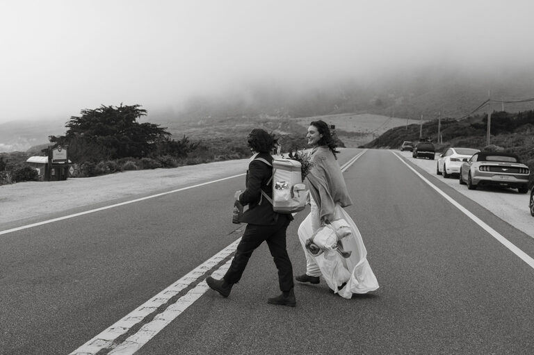 a newlywed couple walks across highway 1 in Big Sur to Garrapata Beach