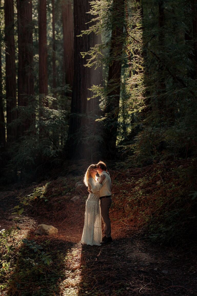 newlyweds in beam of light in a redwood forest in big sur